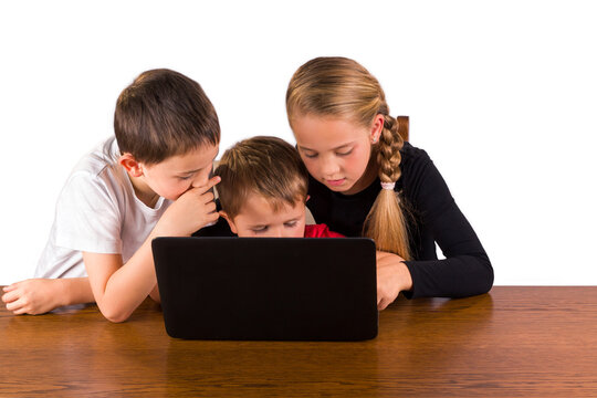 A Cute 4 Year Old Toddler Having Fun With A Laptop Computer While His Older Brother And Sister Are Helping Him. Isolated On White Background