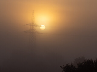  foggy landscape with a big power pole in the sunrise