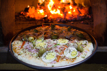 Pizza portuguesa com ovo assada no forno a lenha