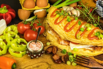 Egg omelette with bacon and sausage. Omelette with tomatoes,  green onion on wooden plate. Frittata - italian omelet. Top view. Flat lay.