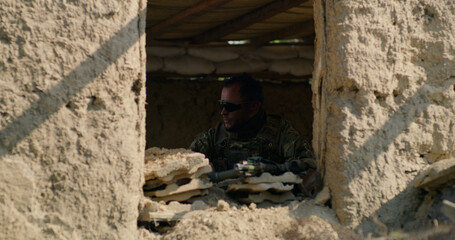 Man guarding desolate building during war