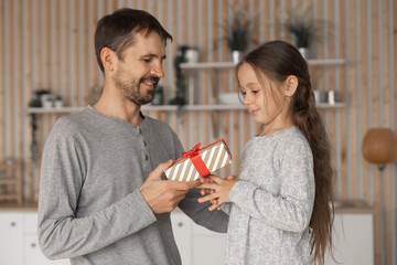 Child daughter congratulating dad and giving him gift box