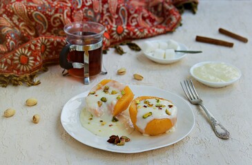 Dessert of stewed quince in syrup, poured with custard on a white plate on a light concrete background. Healthy desserts.