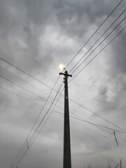 lamp post with lighten bulb in cloudy weather and wires