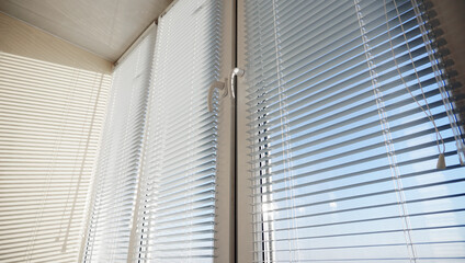 Closed big white plastic window with metal blinds