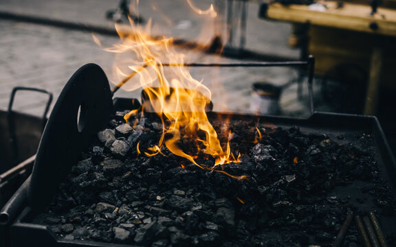 A blacksmith working with simple object by forging the metal. Flame texture close-up. Art, traditional craft, handicraft, history, industry, smithing process, wrought iron and steel details - Powered by Adobe