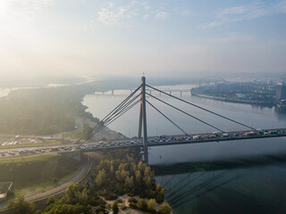 Aerial drone view. North bridge in Kiev in the rays of a sunny morning. Autumn haze in the air, cars are driving across the bridge.