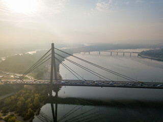 Aerial drone view. North bridge in Kiev in the rays of a sunny morning. Autumn haze in the air, cars are driving across the bridge.