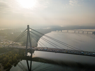 Aerial drone view. North bridge in Kiev in the rays of a sunny morning. Autumn haze in the air, cars are driving across the bridge.