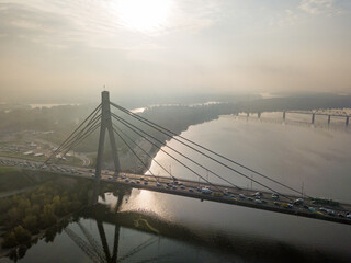 Fototapeta na wymiar Aerial drone view. North bridge in Kiev in the rays of a sunny morning. Autumn haze in the air, cars are driving across the bridge.