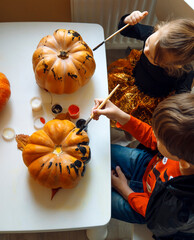 Children in Halloween costumes paint pumpkins. Top view.
