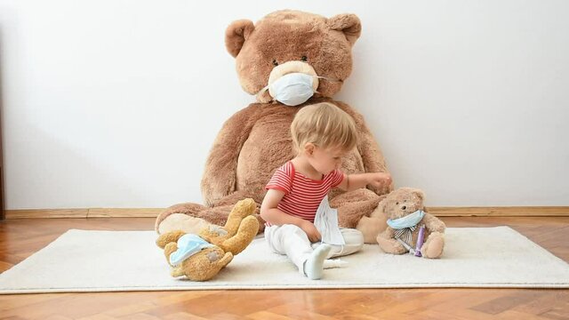 Cute little child playing with his sick teddy bears wearing medical mask against viruses. Role playing, child playing doctor with plush toy. Children and flu, coronavirus illness concept.