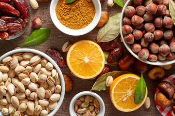 Various raw nuts: hazelnuts, pistachios, chestnuts, dates and oranges.