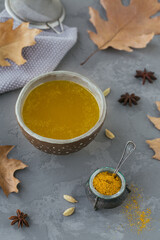 Healthy homemade Ghee or clarified butter in a jar and turmeric powder on grey concrete background. Healthy Ayurveda food concept.
