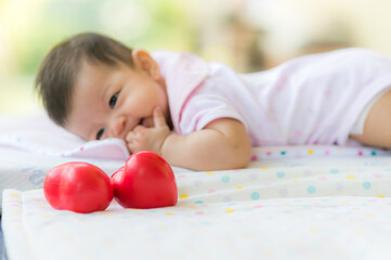 Fototapeta na wymiar Cute asian baby smile and lay on bed with red heart and love