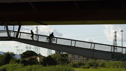 transit of motorcycles and bicycles and pedestrians on a cable-stayed iron bridge over the Arno