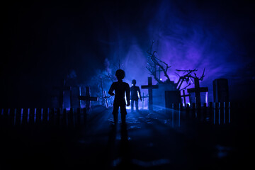 Girl walking alone in the cemetery at night. Dark toned foggy background. Horror Halloween concept