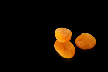 Dried apricots on a black background with reflection
