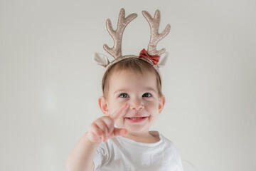Little infant girl with shiny glitter rain deer horns costume. New year and christmas party celebration. Christmas holidays.