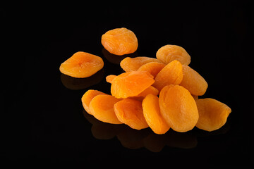 Dried apricots on a black background with reflection