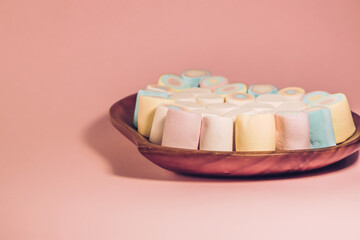 Colorful marshmallow sweets on wooden plate, background with free space for filling