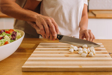Obraz premium Person cutting slice of cheese on cheese plate