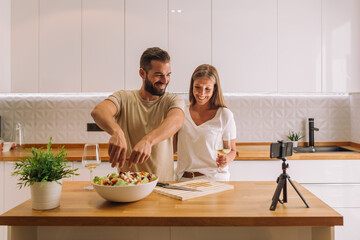 Two food vloggers making video while prepping vegetables in kitchen
