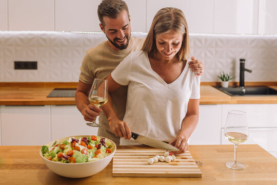 Young Couple Laughing And Working Together With Copy Space In A Nice Kitchen 