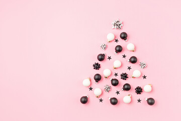 Christmas ornamets laid out in shape of Christmas tree on pink background. Winter holidays greeting card