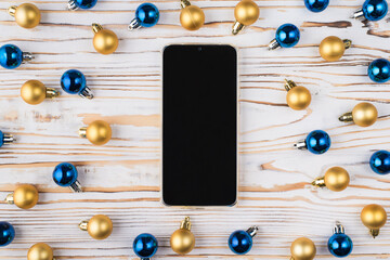 Top above overhead close up view photo of smartphone with black empty blank screen and lot of small toy baubles lie on wooden table desktop