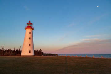 Fototapeta na wymiar Lighthouse and moon during sunset, Prince Edward Island, Canada.