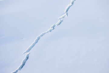 Crack in the ice cover. Snow covered ice. Cracked ice floes on the sea in the Arctic. Polar region. Snow texture. Great for background and design.