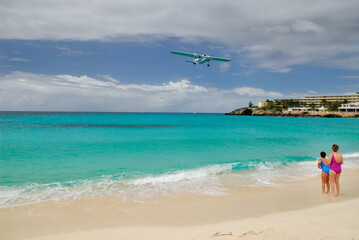 Two female beachgoers watch a plane land in St Maarten