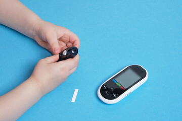 Fototapeta premium small child presses the button glucose meter, blood glucose meter, childhood diabetes, child health care