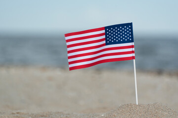 Flag of USA on sandy shore. National flag of America, sea background.