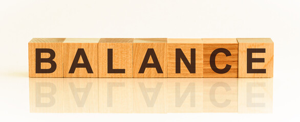 Wooden Blocks with the text: Balance. The text is written in black letters and is reflected in the mirror surface of the table. New business relaunch startup concept