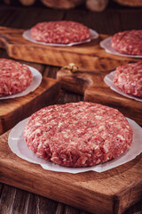 Raw hamburgers on cutting board with wood background - Close-up