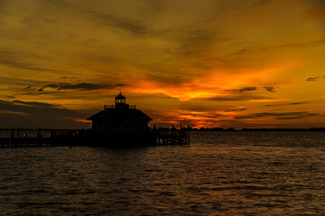 Obraz premium Lighthouse at Sunrise with Orange Sky