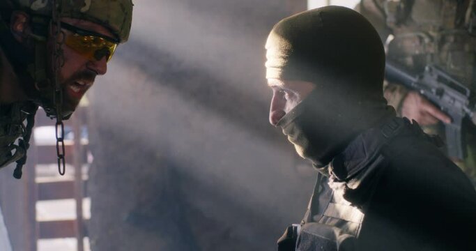 Angry soldier interrogating mature terrorist