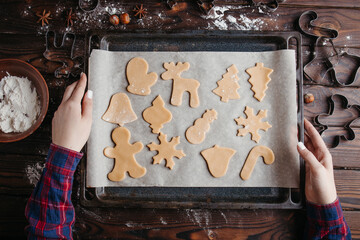 Woman hold oven-tray with raw gingerbread cookies