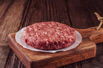 Raw hamburger on cutting board with wood background - Close-up