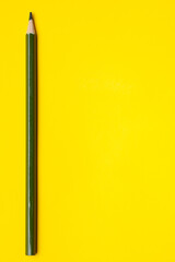 vertical dark green sharp wooden pencil on a bright yellow background, isolated, copy space, mock up.