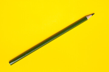 diagonal dark green sharp wooden pencil on a bright yellow background, isolated, copy space, mock up.