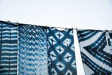 Beautiful natural indigo tie dye fabric hanging outdoor under the blue sky. Indigo dyed fabric in...