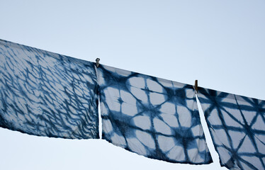 Beautiful natural indigo tie dye fabric hanging outdoor under the blue sky. Indigo dyed fabric in...