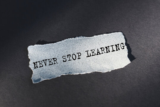 Light blue torn paper on dark background with word Never Stop Learning