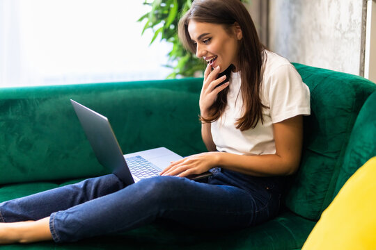 Young beautiful woman using a laptop computer sitting on cauch at home
