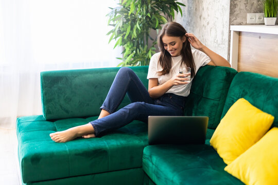 Young beautiful woman using a laptop computer sitting on cauch at home