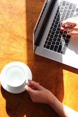 Woman working at home with laptop and a hot water drink