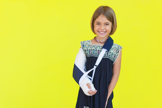 lachendes Kind mit einem Gips vor gelber Wand